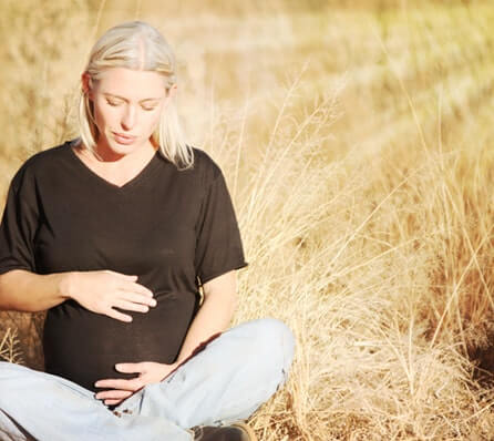 Pregnant woman sitting in a field